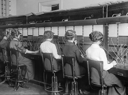 Group of female telephone operators at a large switchboard in 1914